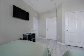 A bedroom with two beds, a TV mounted on the wall, and white doors. - Vc13-303 - 3BR Condominium Near Parks (Orlando)