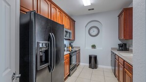 Una cocina moderna con armarios de madera, un refrigerador de acero inoxidable, un microondas y un lavaplatos.
