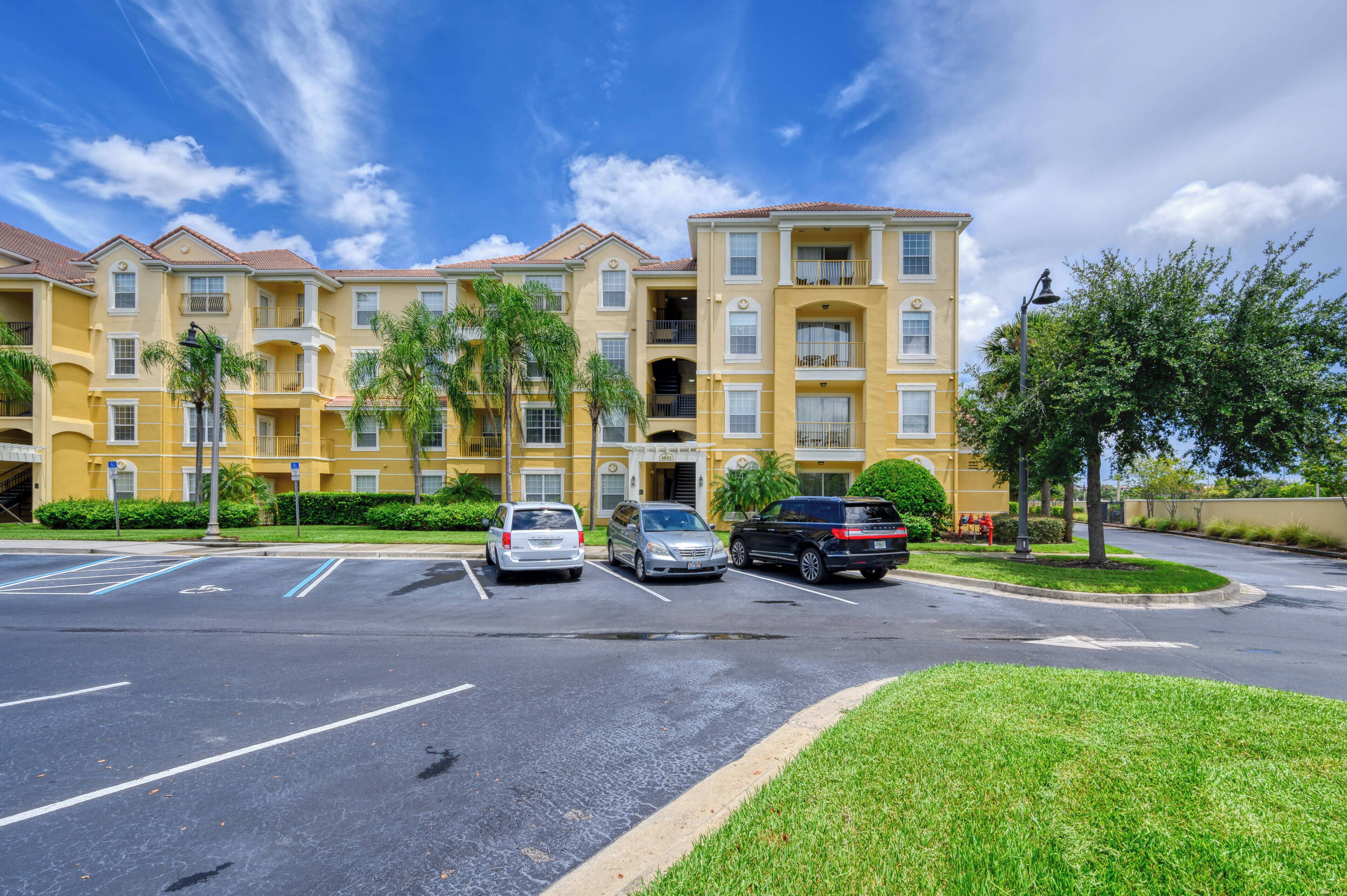 A multi-story residential building with a parking lot in front.