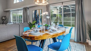Un coin repas avec une table ronde en bois, des chaises bleues et un lustre.