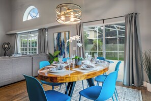 Ein Essbereich mit einem runden Holztisch, blauen Stühlen und einer Chandelier.