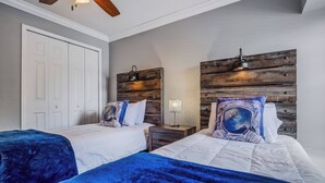 Une chambre avec deux lits, une tête de lit en bois, une table de chevet et une porte.