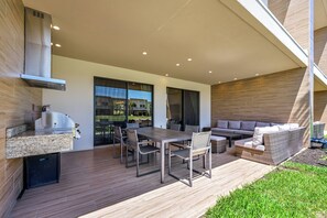 Une terrasse extérieure avec une table à manger, des chaises, un barbecue et un canapé.