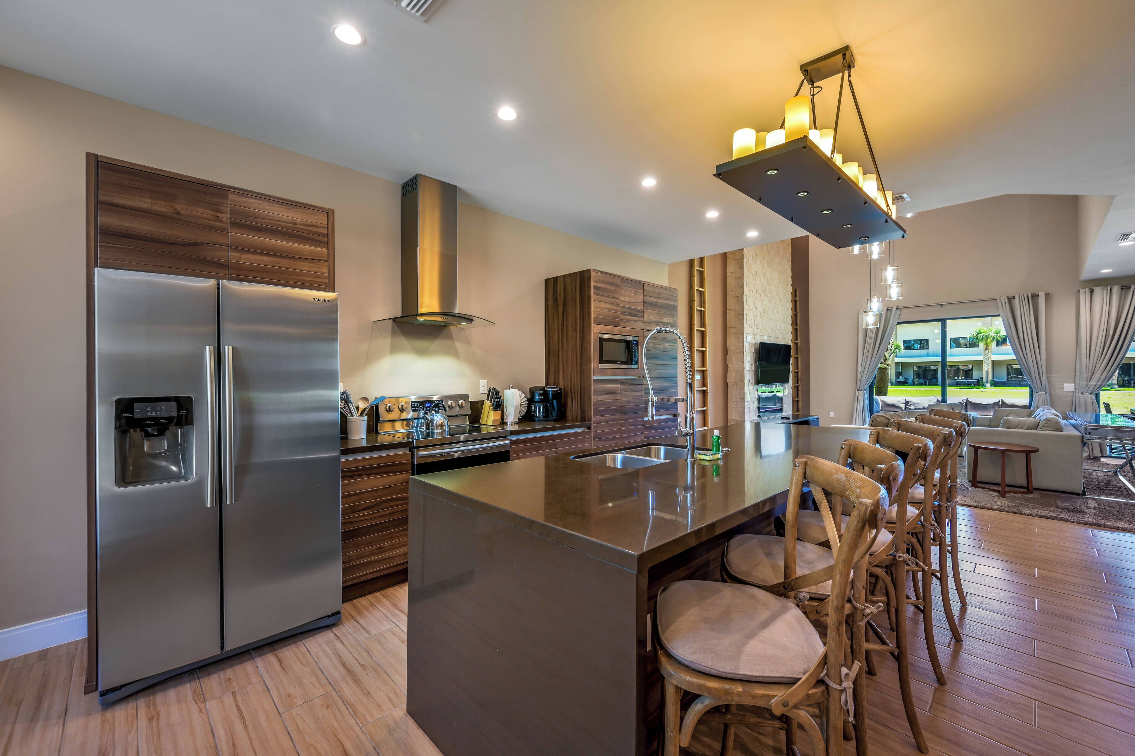 Una cocina moderna con un refrigerador de acero inoxidable, horno empotrado y una isla grande con taburetes de bar.