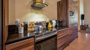 A modern kitchen with a stainless steel stove, a built-in oven, and a range hood. There is a wooden cabinet with a microwave and a coffee maker on the counter. - Mvv7482 - 3BR House Near Disney at Magic Village (Kissimmee)