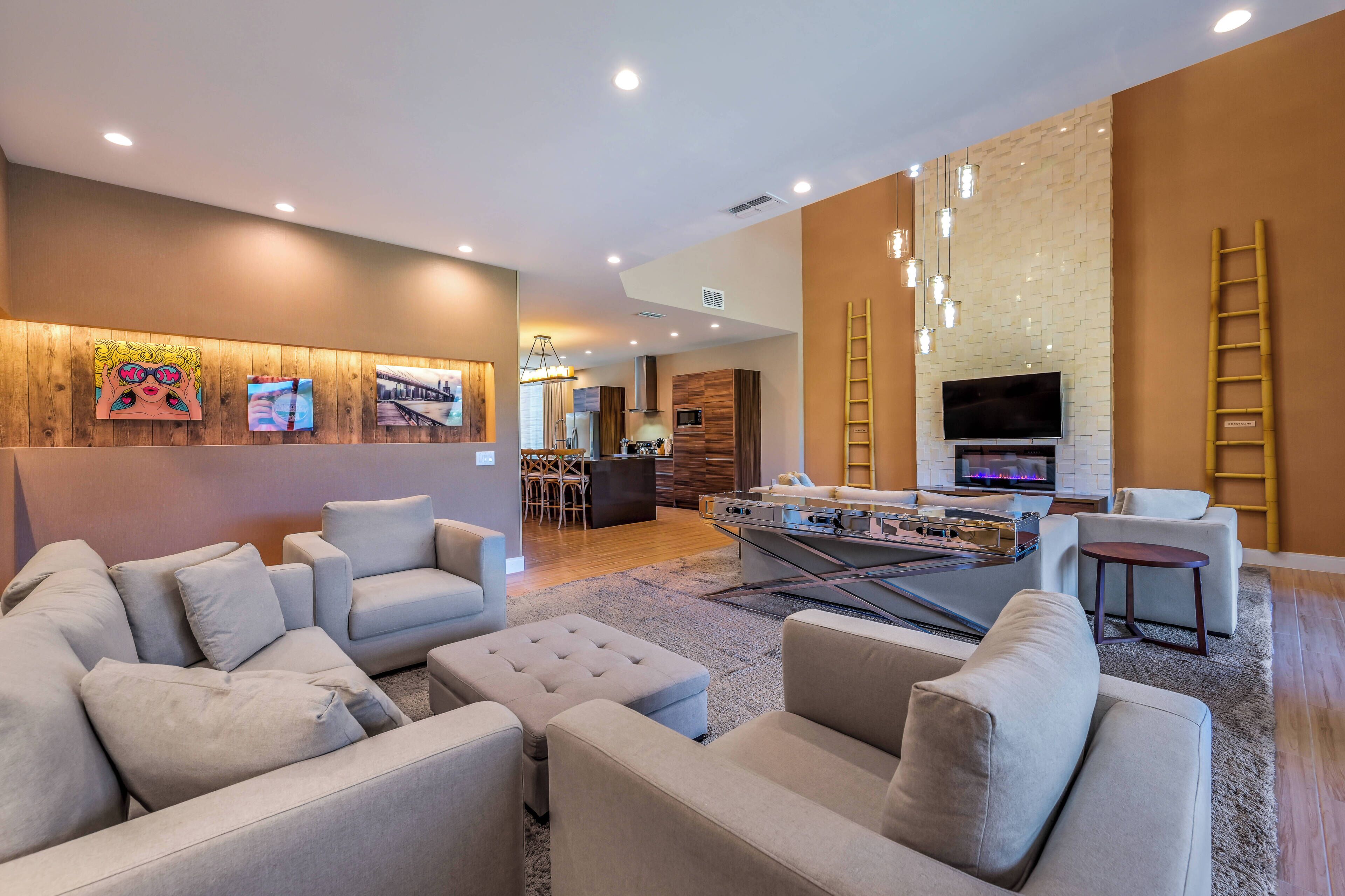 A modern living room with sofas, a coffee table, and a TV. There is a kitchen area in the background with a dining table and chairs.