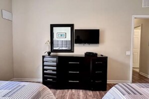 Ein Schlafzimmer mit Bett, Kommode, Spiegel und Fernseher.