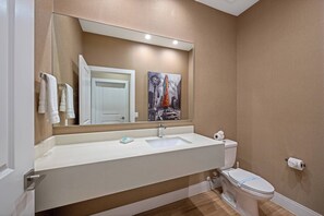 A bathroom with a white sink, a toilet, and a large mirror. - Mvv7485 - 3BR House Near Disney With Hot Tub (Kissimmee)