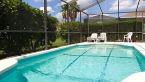 A swimming pool with a covered area, surrounded by white chairs and greenery. - Sv2925 - 4BR House With Pool Near Disney Parks (Kissimmee)