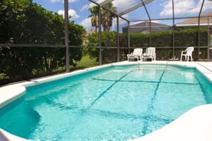 A swimming pool with a covered area, surrounded by white chairs and greenery. - Sv2925 - 4BR House With Pool Near Disney Parks (Kissimmee)