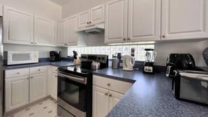 A modern kitchen with white cabinets, a black stove, a microwave, and a coffee maker. - Sv2925 - 4BR House With Pool Near Disney Parks (Kissimmee)