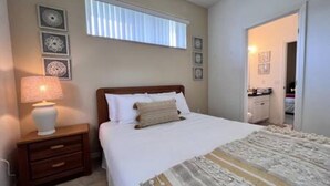 A bedroom with a bed, a nightstand, a lamp, and a window with blinds. - Sv2925 - 4BR House With Pool Near Disney Parks (Kissimmee)
