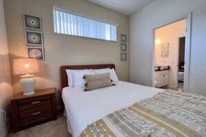 A bedroom with a bed, a nightstand, a lamp, and a window with blinds. - Sv2925 - 4BR House With Pool Near Disney Parks (Kissimmee)