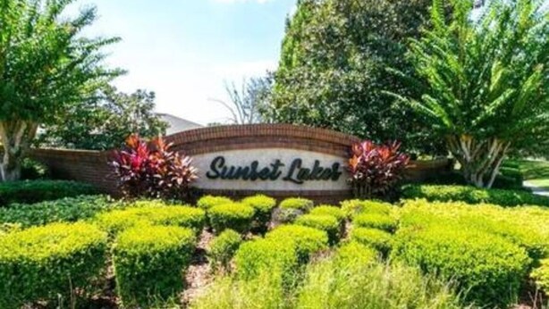 A landscaped area with a sign reading "Sunset Lake." - Sv2925 - 4BR House With Pool Near Disney Parks (Kissimmee)