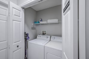 A laundry room with two stacked washers and dryers, a shelf with folded towels, and a wall-mounted laundry basket. - Hl137 - 5BR House With Pool Near Disney Area (Davenport)