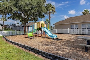 A playground with a slide, climbing structures, and a fenced area. - Hl137 - 5BR House With Pool Near Disney Area (Davenport)