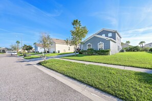 A residential street with houses, well-maintained lawns, and a clear blue sky. - Hl137 - 5BR House With Pool Near Disney Area (Davenport)