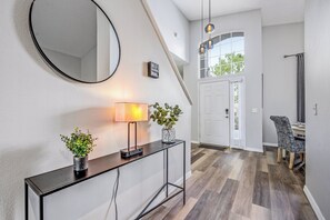 A modern entryway with a console table, a mirror, a lamp, and a potted plant. - Hl137 - 5BR House With Pool Near Disney Area (Davenport)