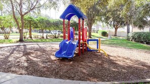 A playground with a blue slide and red and yellow play structures. - Hl137 - 5BR House With Pool Near Disney Area (Davenport)