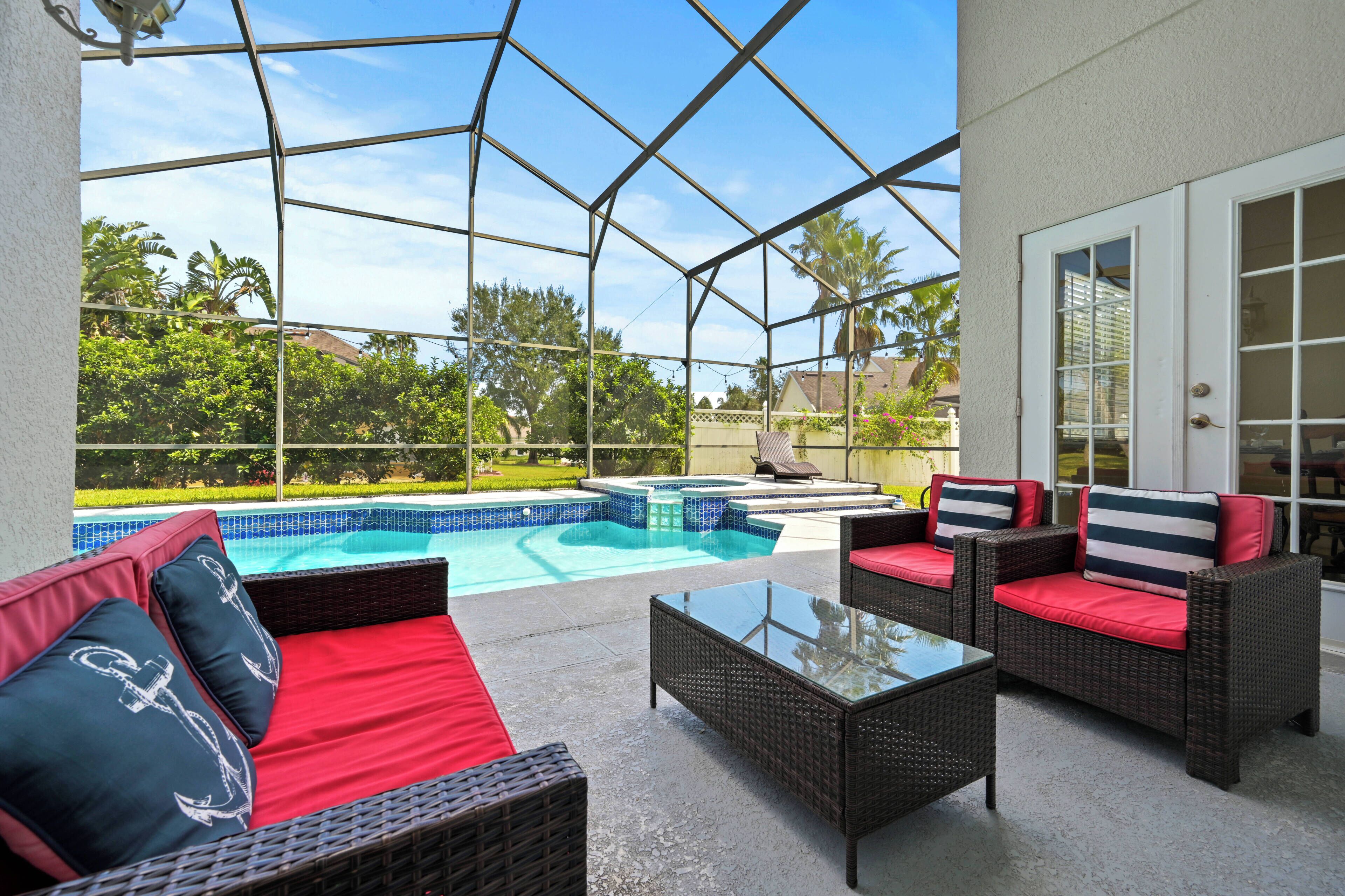 A covered outdoor area with a pool, wicker furniture, and a glass table.