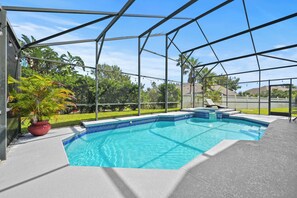 A covered outdoor swimming pool with a clear blue water feature, surrounded by a metal frame structure. - Fg7909 - 6BR House With Private Pool Near Disney (Kissimmee)