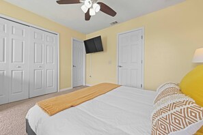 A bedroom with a bed, a ceiling fan, a TV mounted on the wall, and white doors. - Fg7909 - 6BR House With Private Pool Near Disney (Kissimmee)