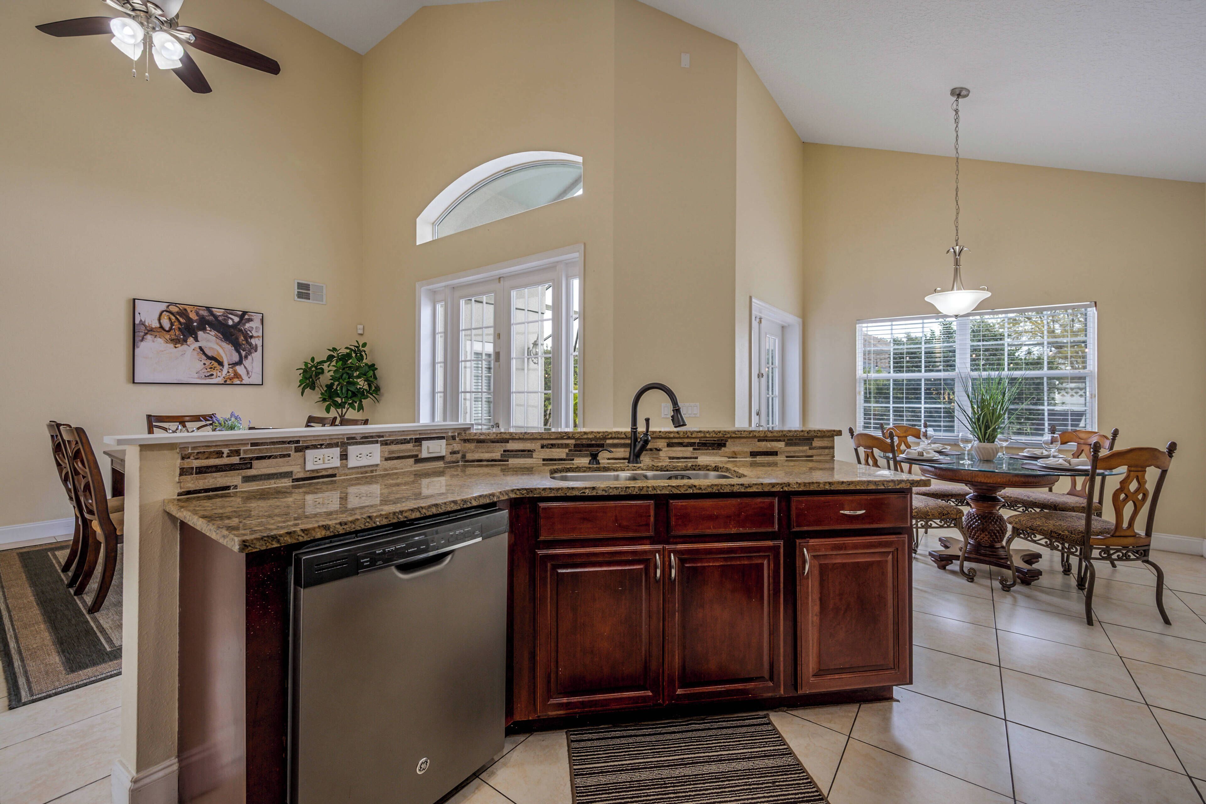 A kitchen with a dishwasher, a sink, and a dining area with a table and chairs.