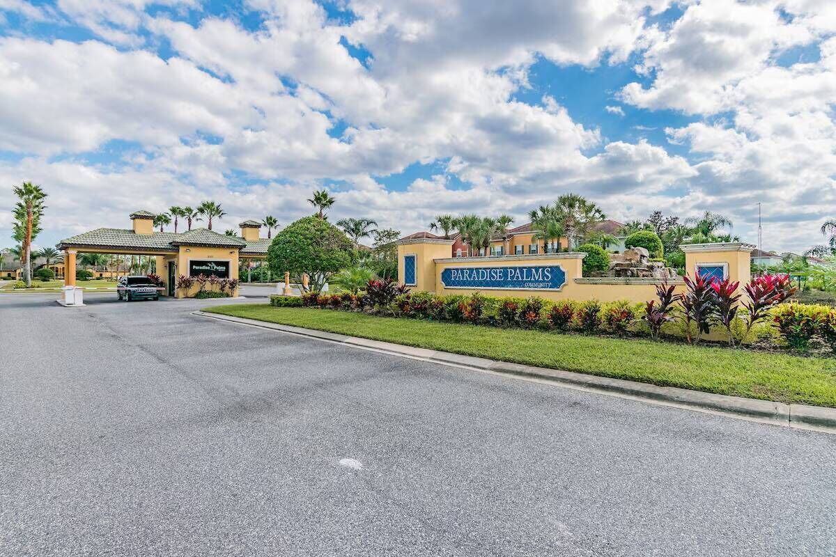 A gated community entrance with a sign reading "Paradise Palms Community."