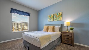A bedroom with a bed, a nightstand, a lamp, and two wall art pieces. - Vc11-405 - 3BR Condo With Resort Access in Orlando (Orlando)