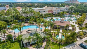 A resort with multiple swimming pools, palm trees, and a large building in the background. - Vc11-405 - 3BR Condo With Resort Access in Orlando (Orlando)