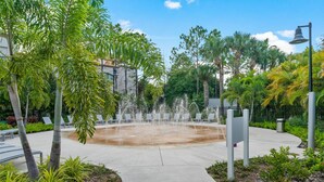 A fountain surrounded by palm trees and a pathway leading to a seating area. - Vc11-405 - 3BR Condo With Resort Access in Orlando (Orlando)