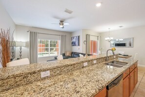 Una cocina moderna con encimeras de granito, lavavajillas integrado y un comedor con sofá y sillones.