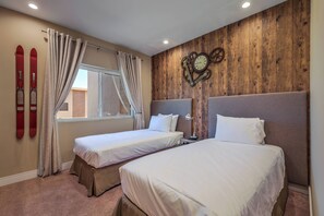 Une chambre d’hôtel avec deux lits, un mur en bois, une horloge et du matériel de ski.