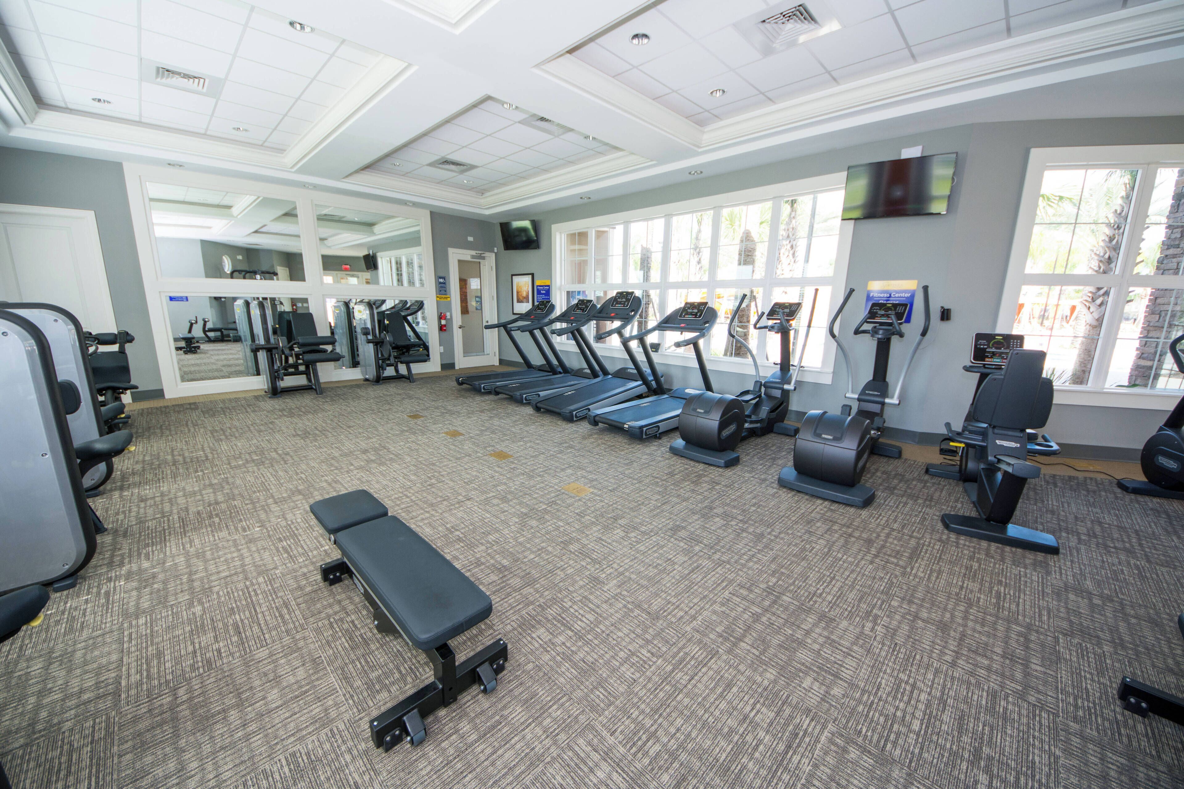 A gym with treadmills, elliptical machines, and weight stations.