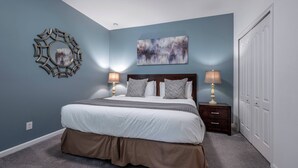 Een slaapkamer met een bed, nachtlampjes, een spiegel aan de muur en een schilderij.