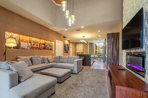 A modern living room with a sectional sofa, a wooden coffee table, and a flat-screen TV. - Mvv7561 - 4BR House Near Disney World (Kissimmee)