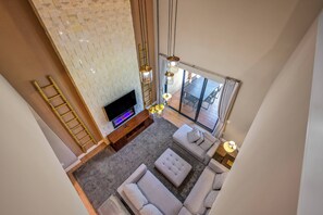 Un salon moderne doté d’un téléviseur à écran plat, d’un meuble de rangement en bois, d’un canapé d’angle gris et d’une grande fenêtre agrémentée de rideaux.