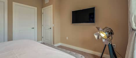 Un dormitorio con una cama, un televisor montado y un trípode con luz.