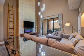 Ein modernes Wohnzimmer mit einem Glastisch, beerenfarbenen Sofas, einem Flachbildfernseher und einem Kamin.