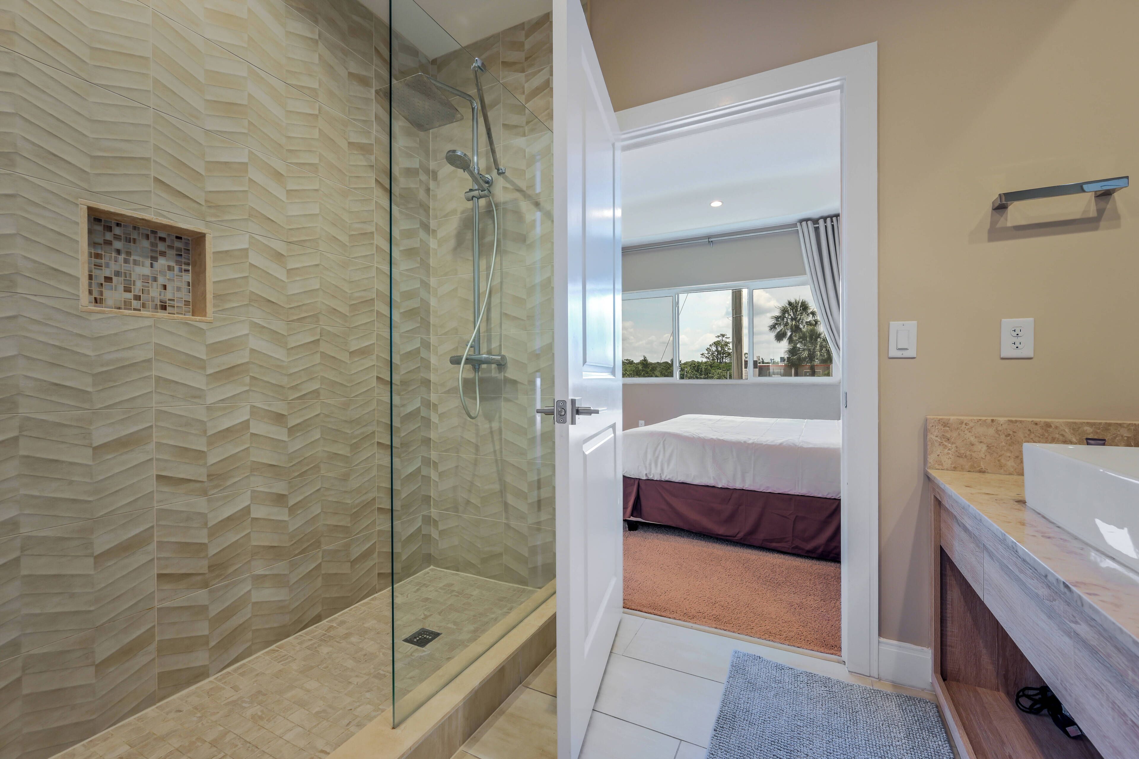 Un baño moderno con ducha de vidrio, un espejo grande y un tocador con lavamanos.