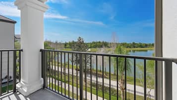 A balcony with a view of a lake, a white building, and a metal railing.