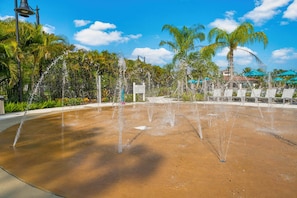 A water fountain with multiple jets, surrounded by palm trees and a clear blue sky. - Is2-310 - 3BR Condo Near Disney and Universal (Orlando)