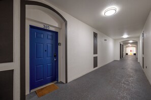 A hallway with a blue door labeled 305, white walls, and a grey floor. - Is3-305 - 3BR Condo With Lake View Near Disney (Orlando)
