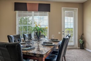 A dining area with a marble table, black leather chairs, and a potted plant. - Vc10-208 - 3BR Large Condo Near the Attractions (Orlando)