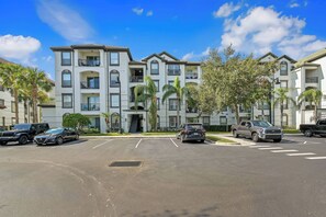 A multi-story residential building with a parking lot in front. - Is1-107 - 2BR Condominium Near Disney (Orlando)