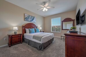 A bedroom with a bed, nightstands, a dresser, a ceiling fan, a window with blinds, and a mounted TV. - Vc8-410 - 3BR Condo With hot tub Near Disney (Orlando)