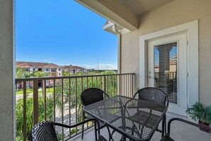 A balcony with a table and chairs, a door with a window, and a view of neighboring houses. - Vc8-410 - 3BR Condo With hot tub Near Disney (Orlando)