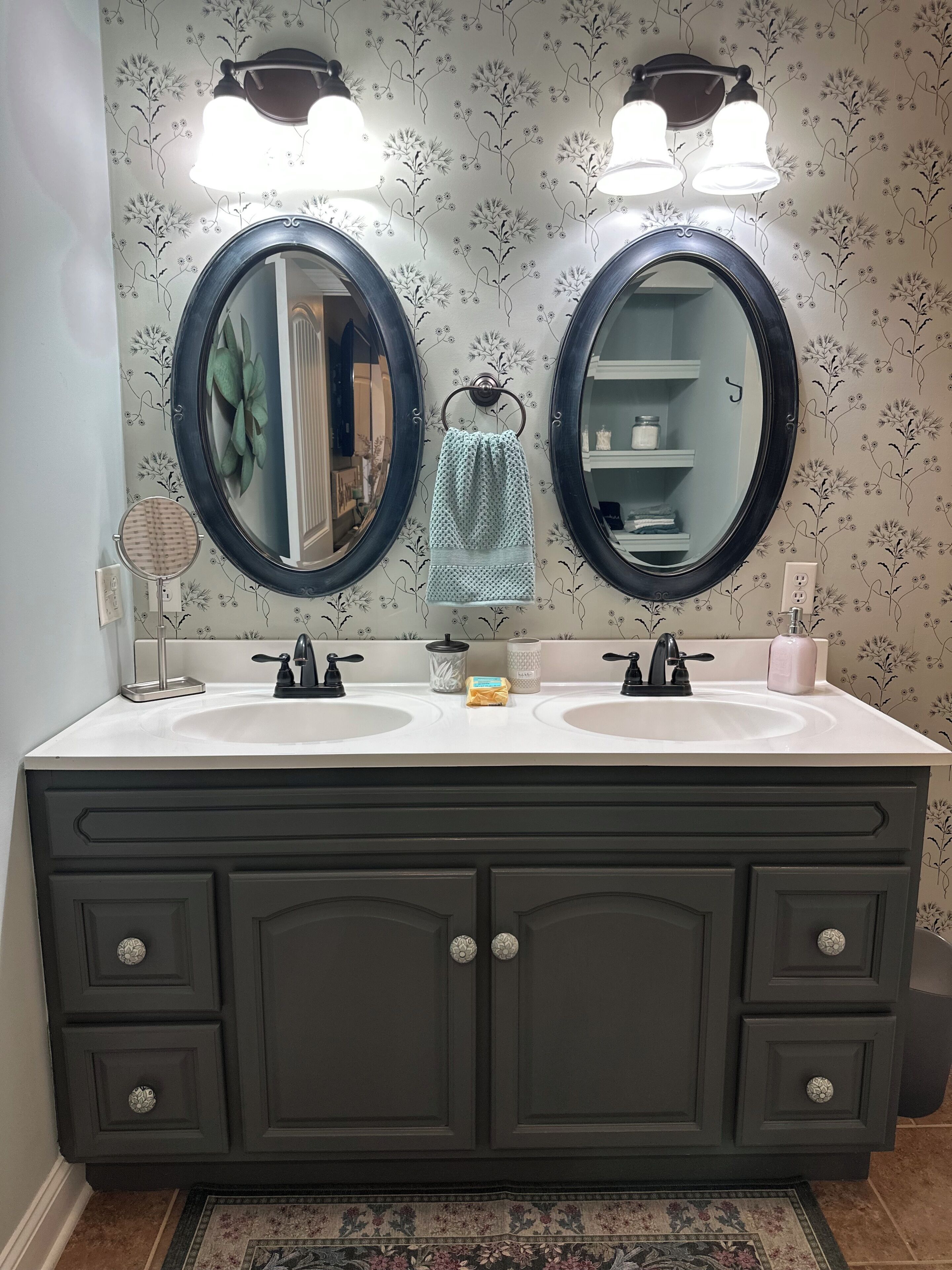 Un bagno con due specchi circolari, un mobile doppio lavabo e carta da parati decorata.