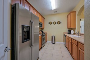 Eine Küche mit Holzschränken, einem Edelstahl-Kühlschrank, einer Mikrowelle und einem Spülbecken.