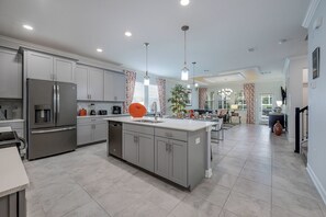 Una cocina moderna con gabinetes grises, electrodomésticos de acero inoxidable y una isla central.